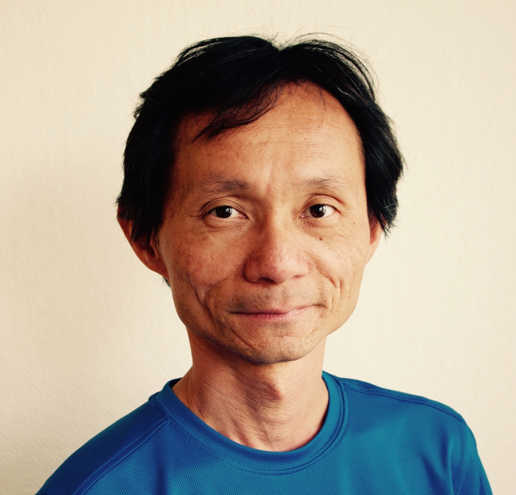 Porträtt Khai Chau i blå tröja
